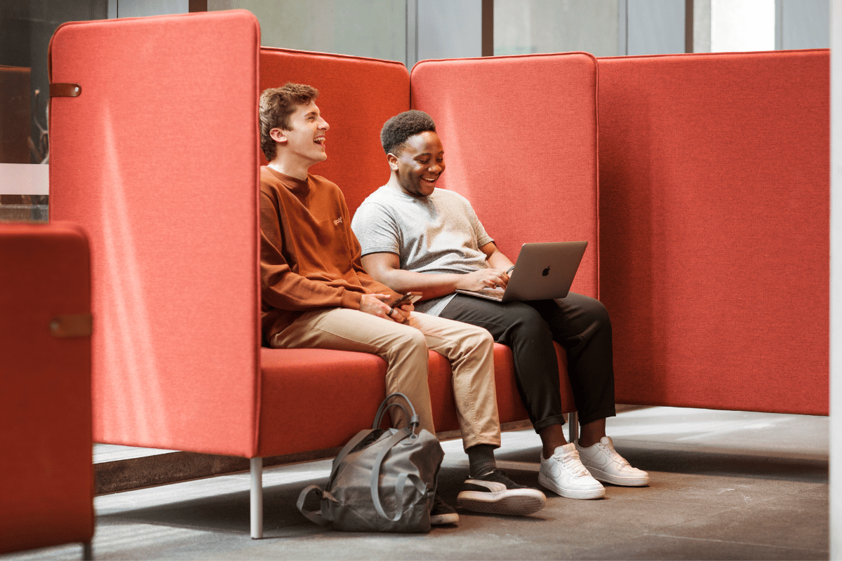Two male students sitting together working on a laptop