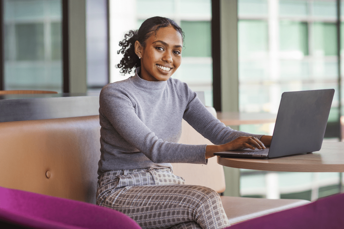 A female student sitting at a desk using her laptop